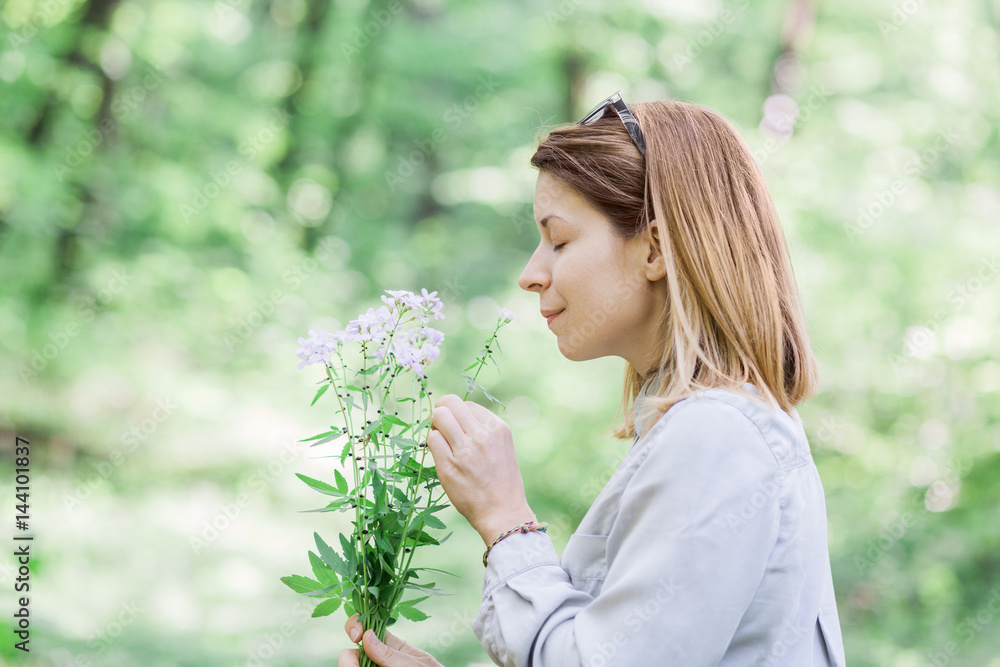 Young woman smelling flowers outside in nature Young woman smelling flowers outside in nature