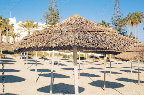 Decorative umbrellas made of palm branches on the background of the beach