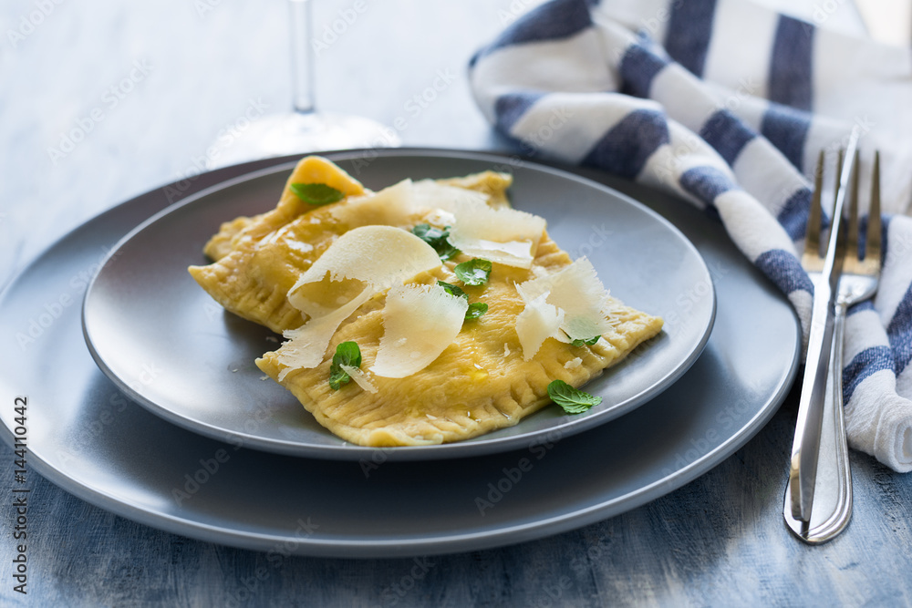 Homemade ravioli with spinach and ricotta cheese with grated parmesan on blue plate. Selective focus Homemade ravioli with spinach and ricotta cheese with grated parmesan on blue plate. Selective focus