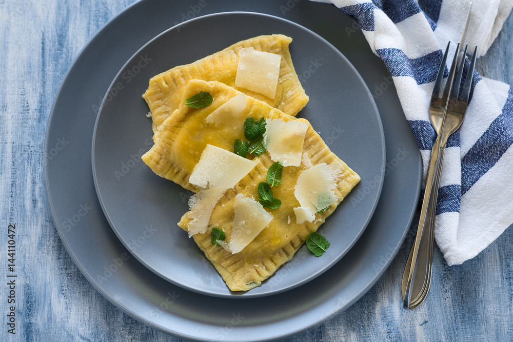 Homemade ravioli with spinach and ricotta cheese with grated parmesan on blue plate. Selective focus Homemade ravioli with spinach and ricotta cheese with grated parmesan on blue plate. Selective focus