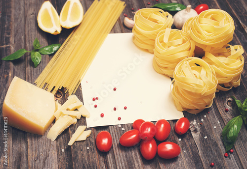 Pasta background with ingredients for cooking around paper, space for text, selective focus.