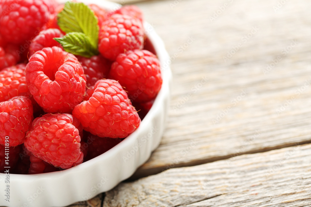 Red raspberries in bowl on a grey wooden table Red raspberries in bowl on a grey wooden table