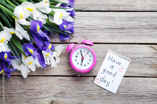 Fototapeta Naklejka Na Ścianę i Meble -  Bouquet of iris flowers with alarm clock on grey wooden table