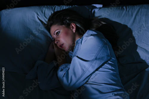Sleep disorder, insomnia. Young blonde woman lying on the bed awake