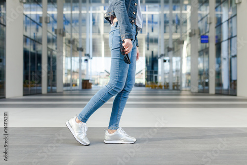 Detail of a woman's legs, in motion. Young woman wearing jeans, dynamic view. Outdoor concept for modern outdoor or lifestyle activities. 