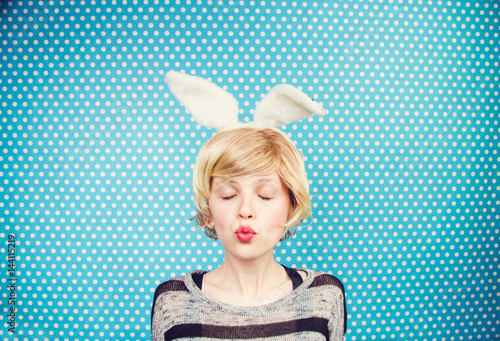 Mujer joven y rubia con orejas de conejo lanzando un beso  photo