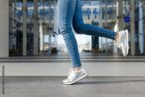 Detail of a woman's legs, in motion. Young woman wearing jeans, dynamic view. Outdoor concept for modern outdoor or lifestyle activities. 
