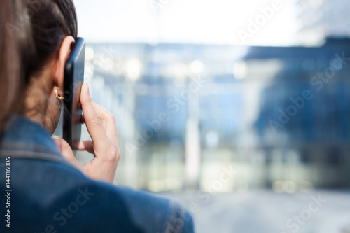 Woman talking on smartphone, back view, with space for text or design concepts.