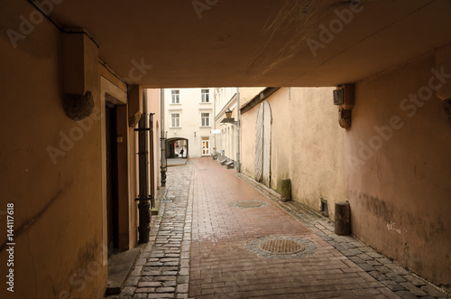 Passage through the courtyard in the old Riga. In the foreground there is an arch in the building. In the background  an arch is also visible.