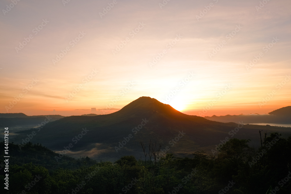 Summer view of soft orange sunset lights in Batur volcano, Kintamani, Bali island of Indonesia. Fantastic outdoor landscape at evening in Southeast Asia, travel adventure photography