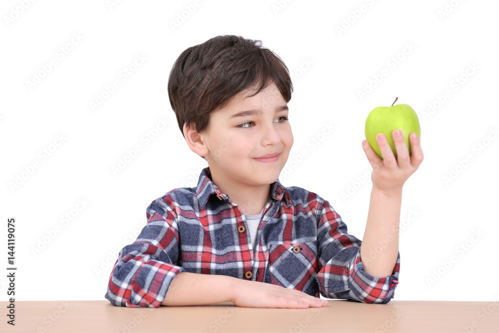 Cute little boy with apple sitting at table, on white background Cute little boy with apple sitting at table, on white background