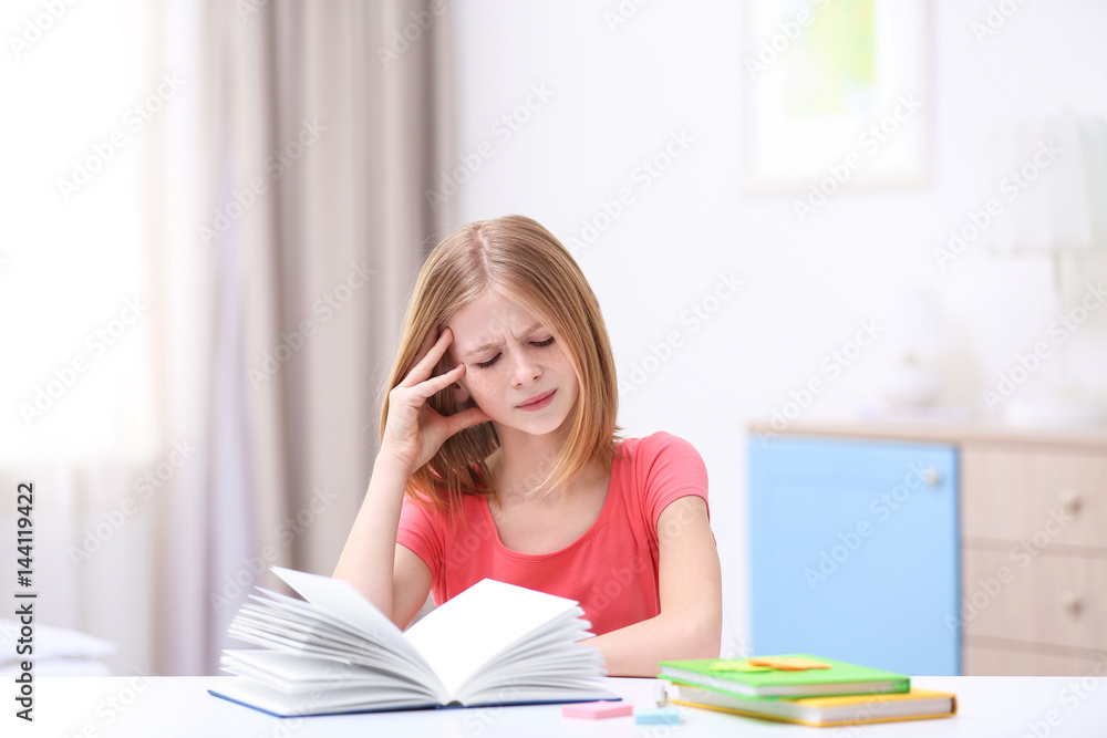 Cute girl suffering from headache while doing lessons at home Cute girl suffering from headache while doing lessons at home