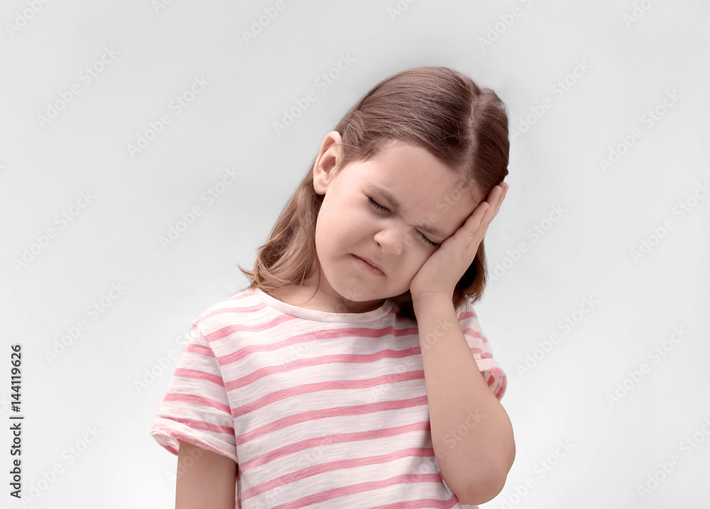 Little girl suffering from headache on light background Little girl suffering from headache on light background