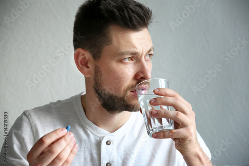 Handsome young man taking pill at home