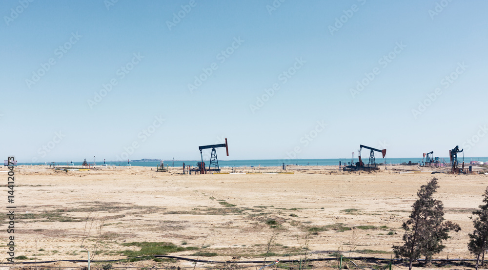A small private oil derrick pumps oil on the field A small private oil derrick pumps oil on the field