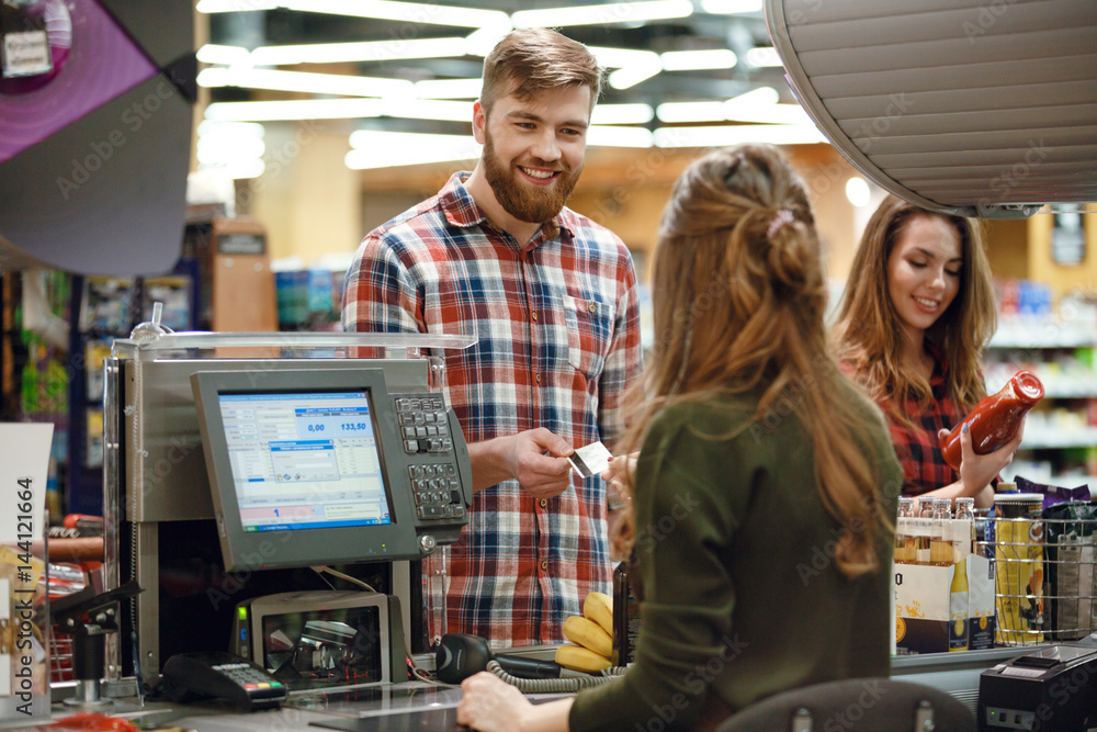 Cheerful young man standing in supermarket shop Cheerful young man standing in supermarket shop