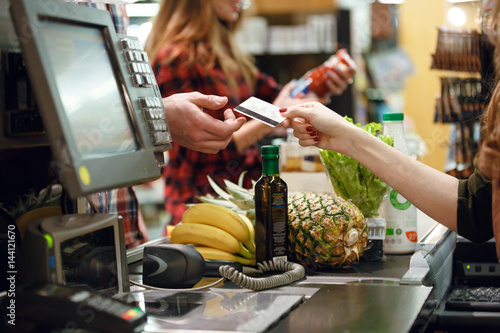 Cropped picture of young man gives credit card to cashier