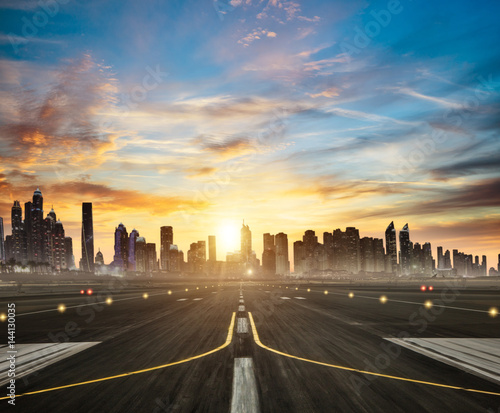 Airport runway with modern city on background in sunset light