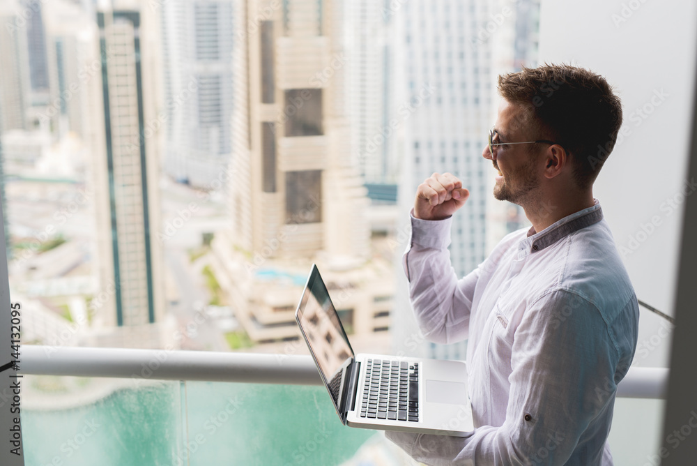 Successful businessman with panoramic city scape office view. Working laptop fist up. Successful businessman with panoramic city scape office view. Working laptop fist up.