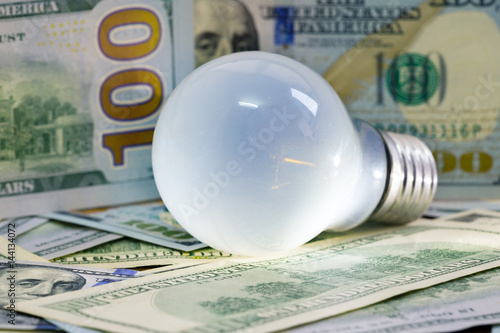 Light bulb on dollar on background. Savings and business idea concept