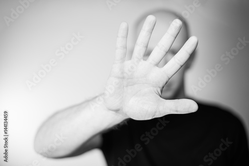 Serious young man showing stop gesture isolated on gray wall background