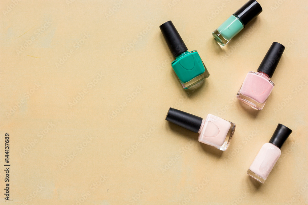 Obraz premium Bottles with nail polish over orange background top view mockup
