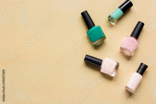 Bottles with nail polish over orange background top view mockup