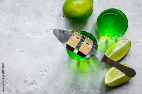 absinthe in glass with lime slices on stone background top view mockup