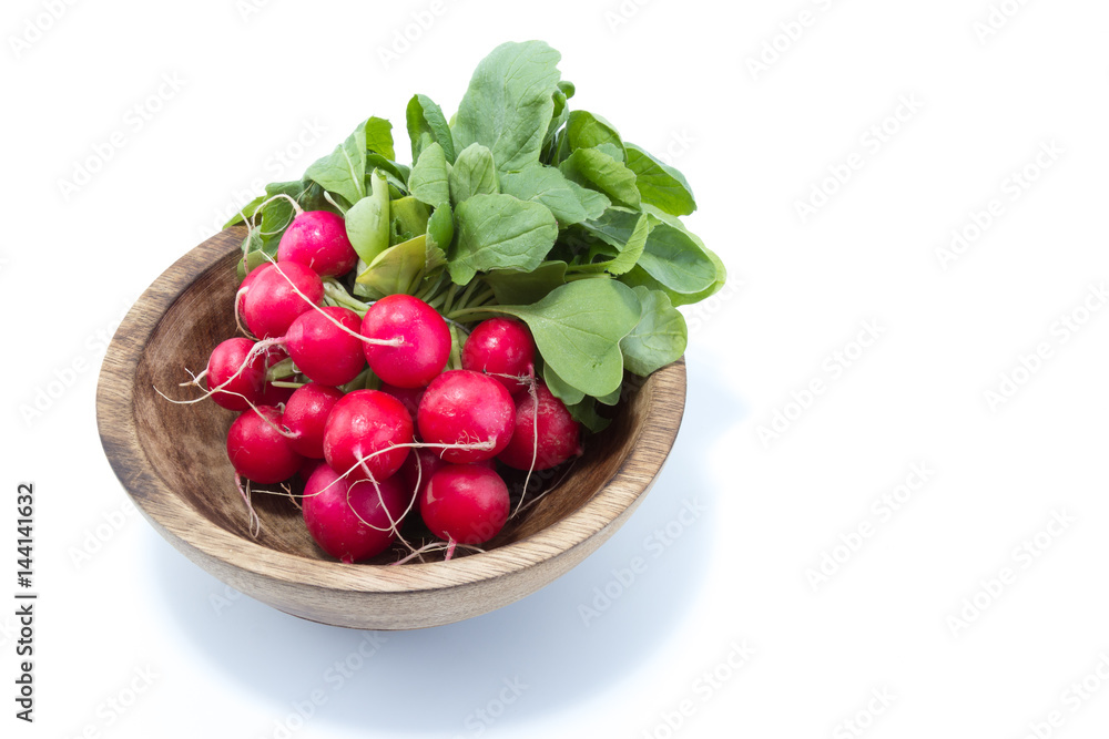 Radish with green leaves in a natural wood bowl isolated in white background - view from the top Radish with green leaves in a natural wood bowl isolated in white background - view from the top