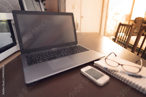 Laptop smart phone glasses and notebook on brown wooden desk in home office