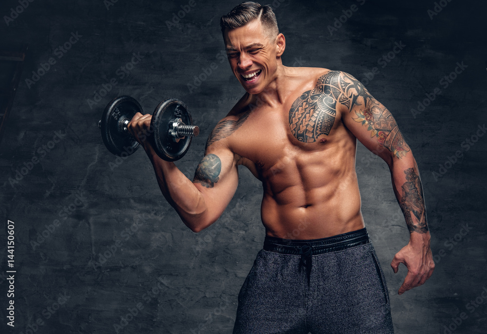 Athletic  male with tattoo on his chest doing biceps workouts with dumbbell.