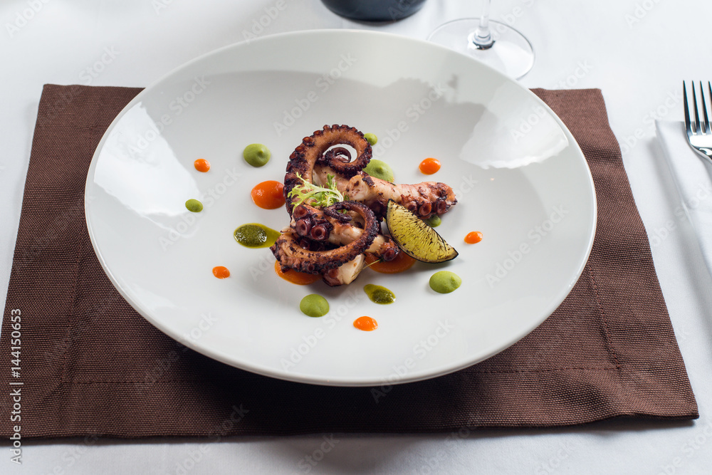 close up of cooked octopus on a white plate close up of cooked octopus on a white plate