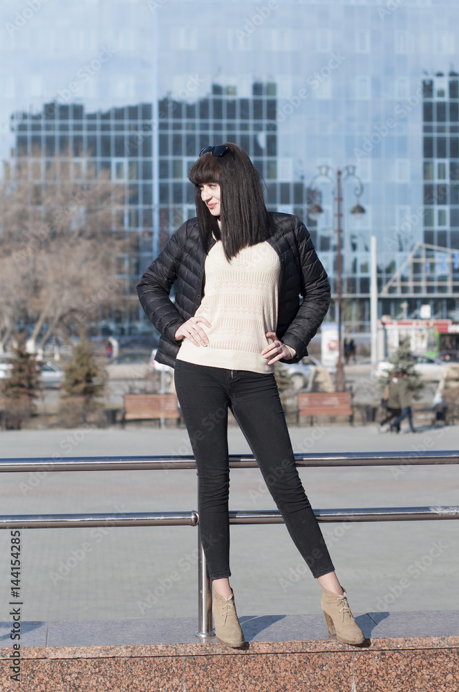 The young woman poses against the background of modern buildings.