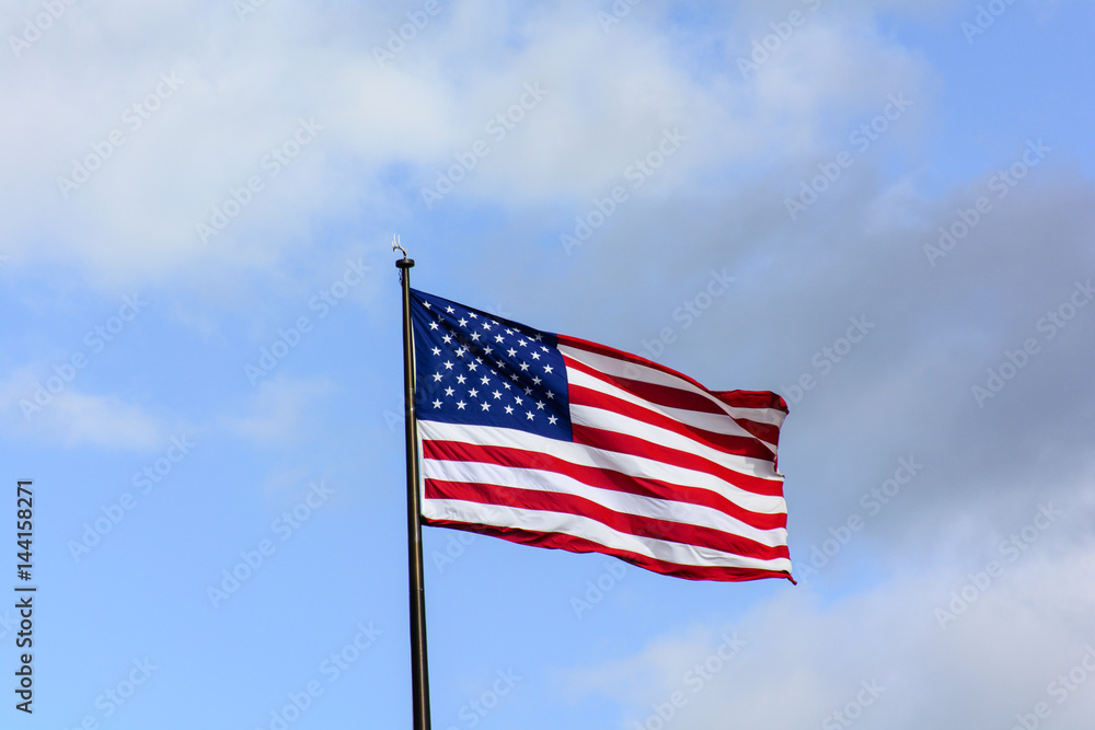 Fototapeta premium USA flag wave in the wind under blue sky