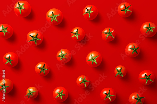 Cherry tomato pattern on a red background. Flat lay, top view © virtustudio