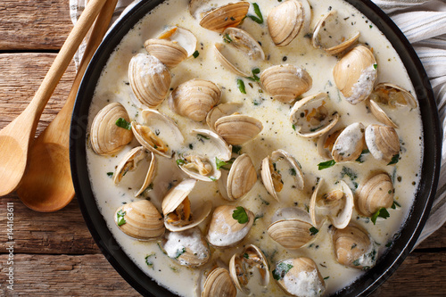 Tasty clams in a creamy sauce with garlic and greens close-up on a table. horizontal top view