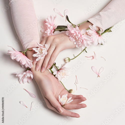 Fashion art portrait woman in summer dress and flowers in her hand with a bright contrasting makeup. Creative beauty photo girls sitting at table on a contrasting pink background with colored shadows