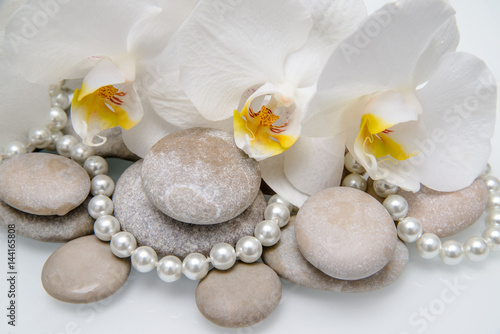  flat stones on a white glass on the background of white orchids 
