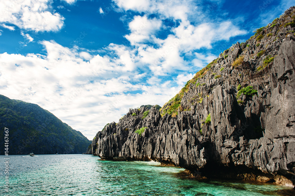 El Nido, Palawan, Philippines. Sharp rocks in lagoon. Blue sky with clouds and clear sea water.