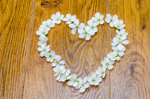 A beautiful heart of flowers. White flowers in the shape of heart on a wooden background