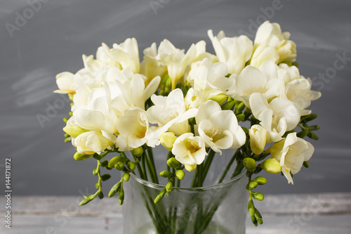Fototapeta Naklejka Na Ścianę i Meble -  White freesia flowers in decorative vase on a background of gray wall