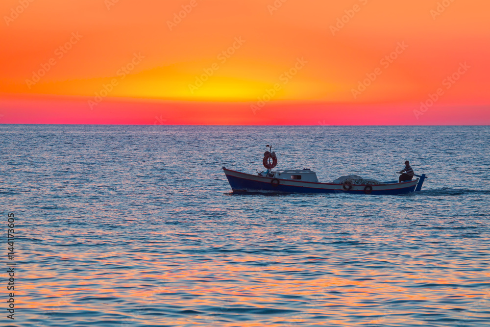 A fisherman departs Alanya Harbor on the Mediterranean sea in Alanya at sunset