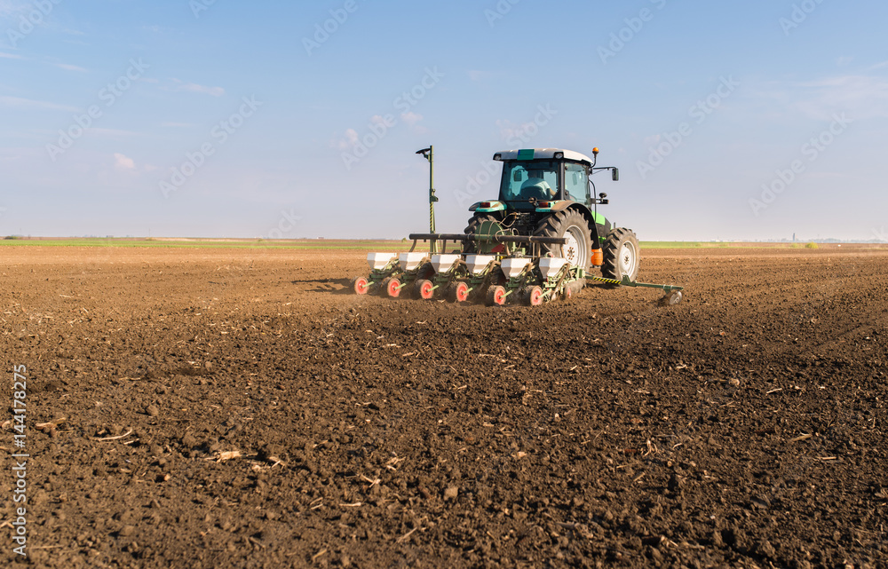 Farmer with tractor seeding - soy sowing crops at agricultural field in spring Farmer with tractor seeding - soy sowing crops at agricultural field in spring