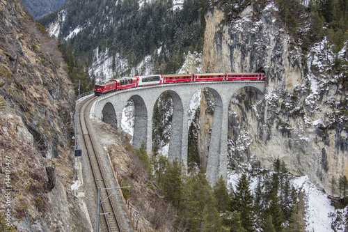 Bernina Express passes through Landwasser Viadukt and snowy woods Filisur Canton of Grisons Switzerland Europe photo