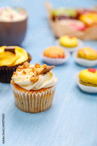 Cupcakes, macaroons and donuts. Mug with whipped cream and marshmallows. Almond macaron cookies. Sweet dessert.