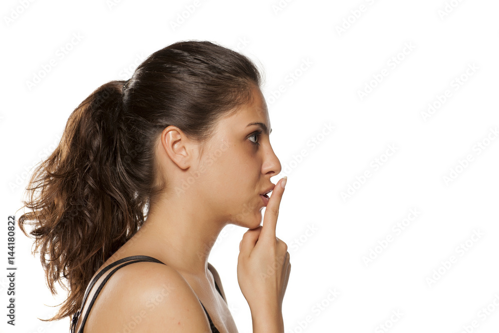 beautiful young woman holding a finger in front of her mouth ... the concept of silence