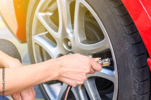 Woman Filling air into a car tire to increase pressure