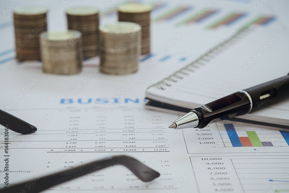 Business diagram on financial report with pen coins and calculator Business diagram on financial report with pen coins and calculator
