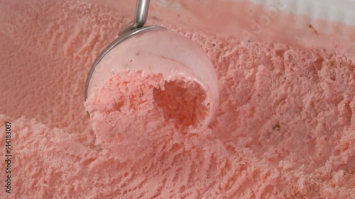 Fruit ice cream scooping out of container by metal spoon in slow motion
