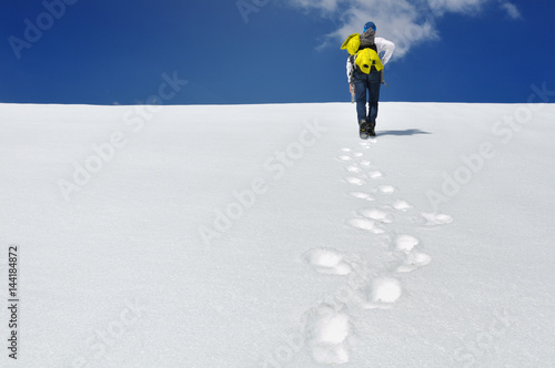 randonneur marchant dans la neige sous ciel bleu